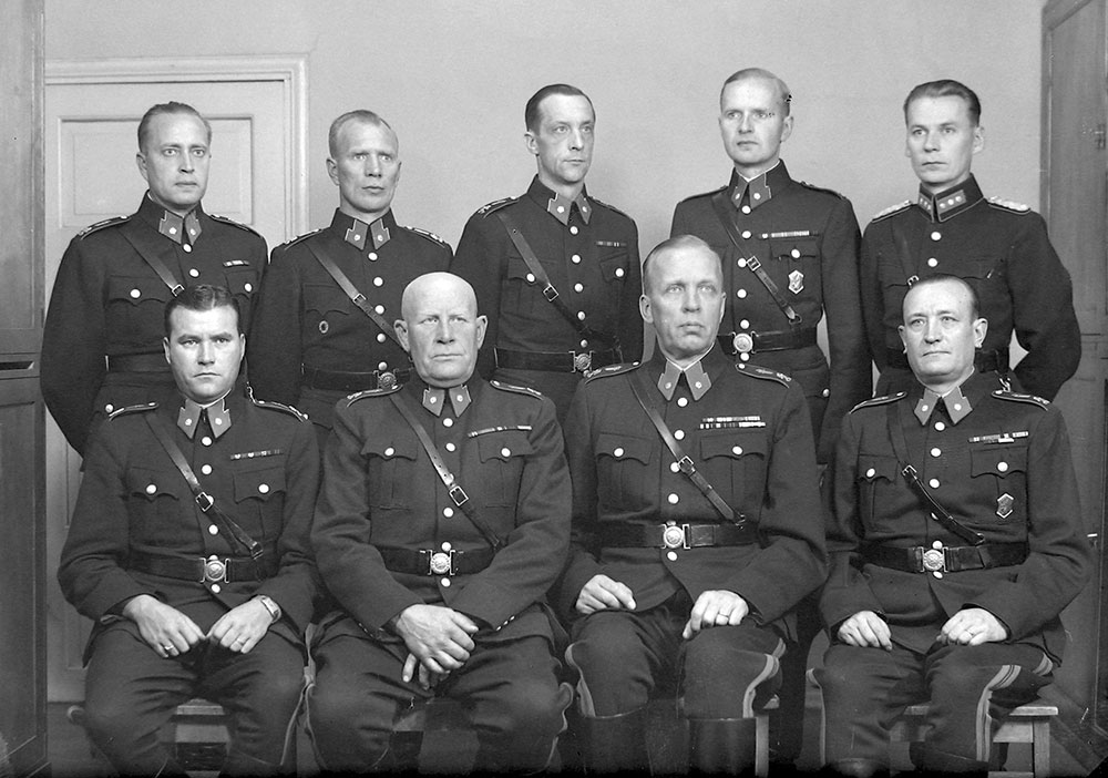 Silverbanden på polisbefälsrockens axlar avskaffades i och med uniformsförordningen från 1941. Banden ersattes med det nya svärdslejonemblemet och ett silverfärgat vapenlejon. Helsingfors polisinrättnings distriktschefer 1946.