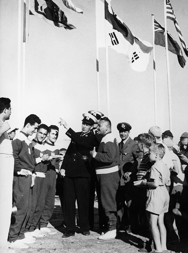 Poliisin pukeutumissuositus Helsingin olympialaisten aikana oli uusi avokauluksinen virkatakki m1951. Poliisikeskusvarikolla oli kisojen aluspäivinä ruuhkaa, kun muualta Suomesta komennetut poliisit jonottivat uutta virkapukua. Kuvan konstaapelit ehtivät saada pukunsa ajoissa.