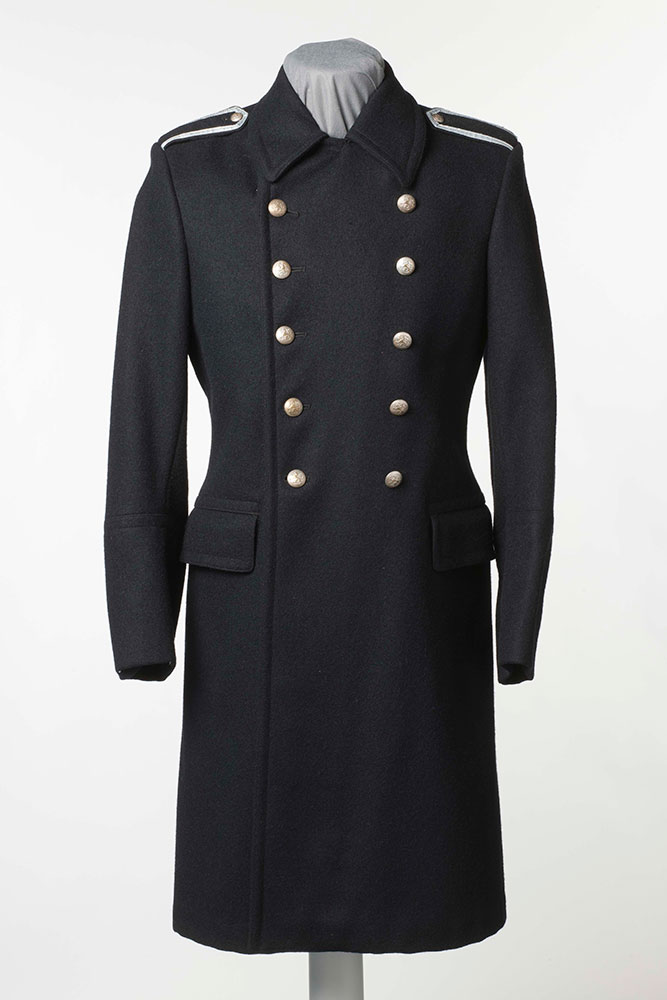 In the early years of Finnish independence (1917–), the police overcoat remained similar to the one used by city policemen at the beginning of the century. According to the uniform statute of 1923, the police coat was to be dark blue, feature buttons in two rows and have pockets sewn on the inside. The shoulder straps of ordinary constables lacked rank insignia, but instead featured a 5 mm wide silver stripe around the edges. Image: Museokuva Matti Huuhka.